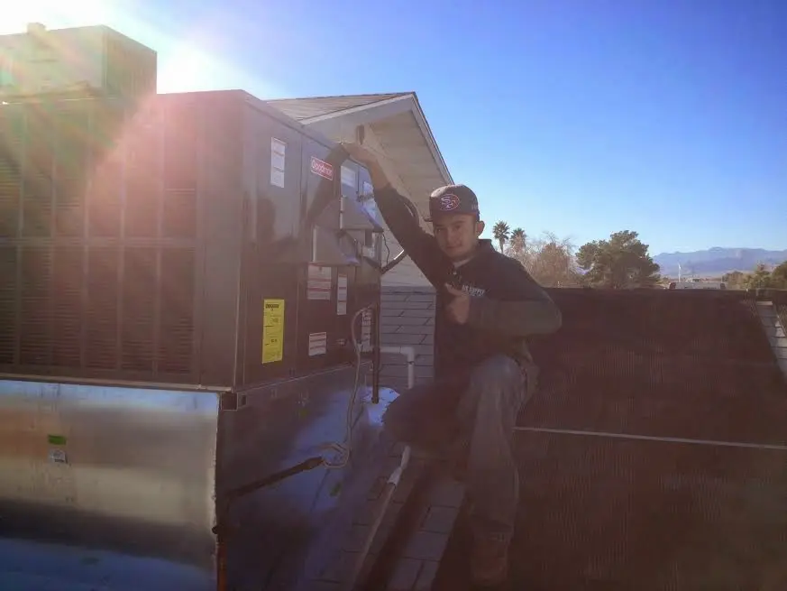 HVAC technician performing Heat Pump Repair on a rooftop unit in Delta